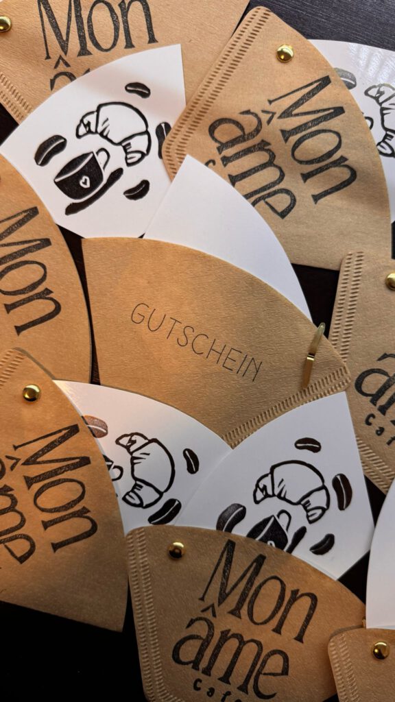 Handgemachte Gutscheine des Mon âme Café Heilbronn aus bedruckten Kaffeefiltern mit Croissant- und Kaffeemotiv